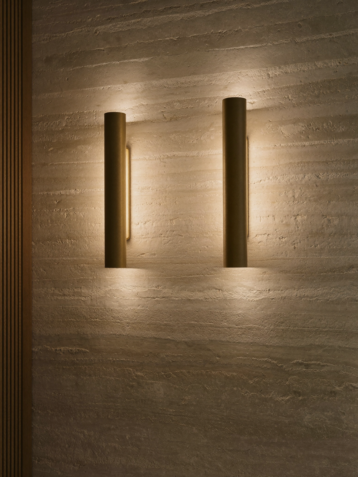 Brass wall sconces casting warm light on a limestone wall