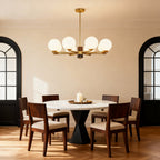 Sculptural chandelier in a warm dining room with arched windows
