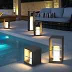 Two black lanterns glowing warmly on a modern patio