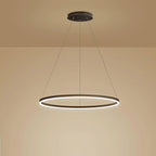 Black ring chandelier glowing warm against a beige wall