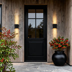 Black up and down sconce softly lighting an outdoor seating area