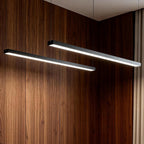 Linear pendant light hanging in front of a wood wall