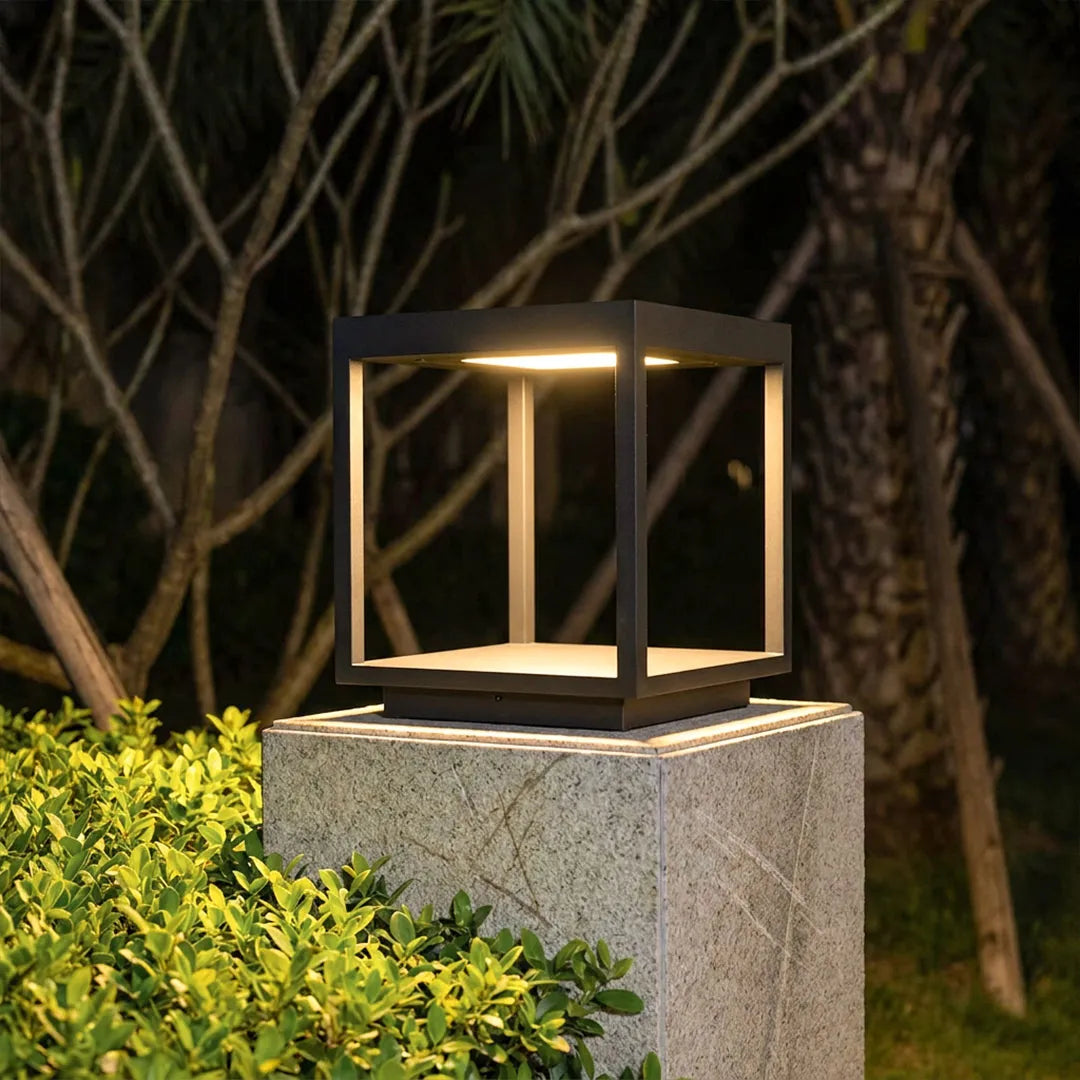 Open-frame pillar light glowing on a garden post at night