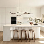 Curved LED pendant light above a white kitchen island counter