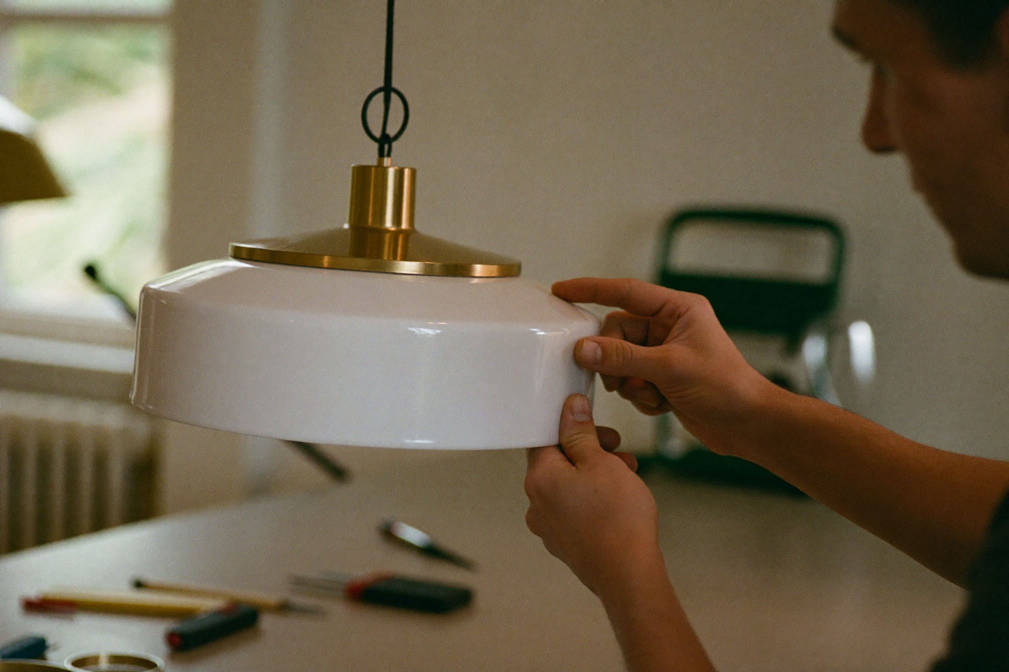 Artisan hands adjusting a brass pendant lamp fitting