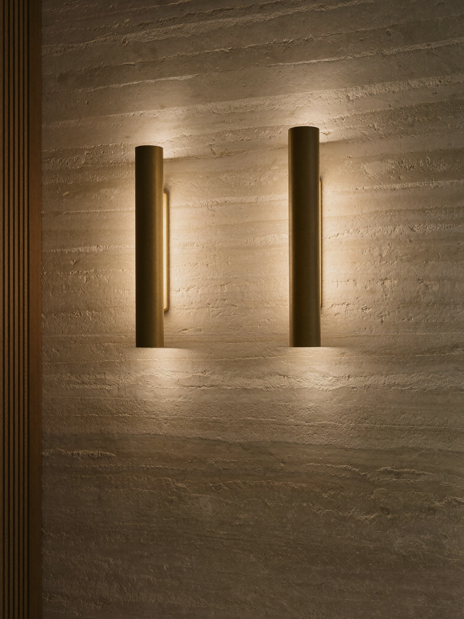 Brass wall sconces casting warm light on a limestone wall
