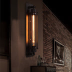 Elongated industrial sconce glowing on a dark brick wall