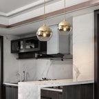 Glass globe pendant light above a marble kitchen counter