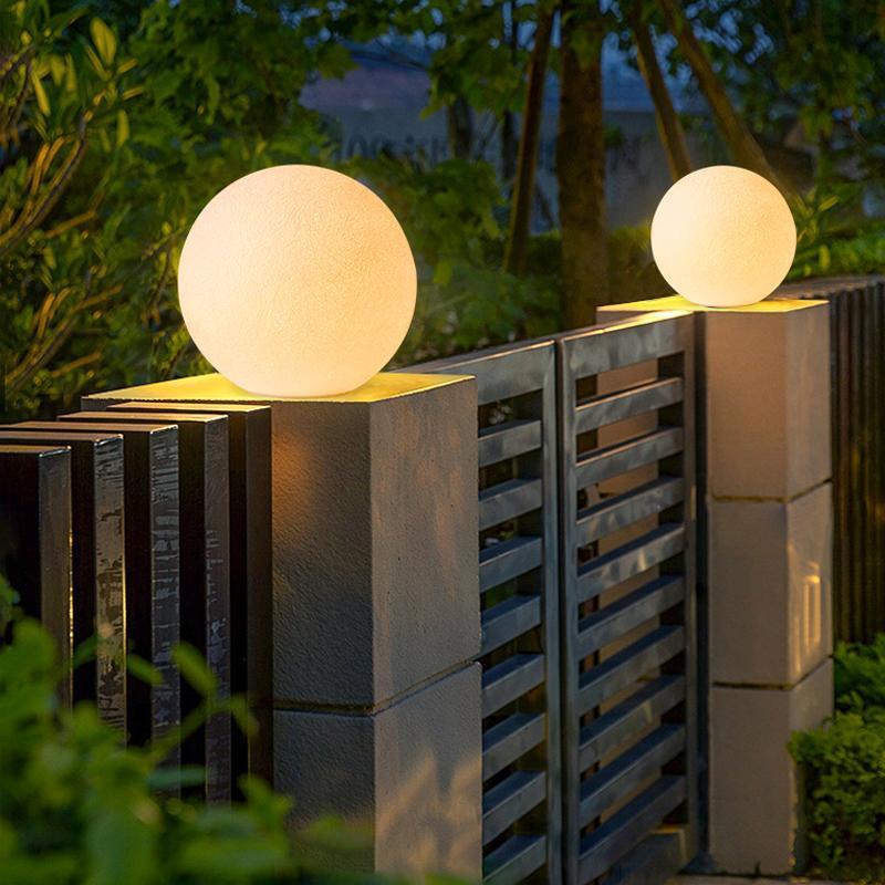 White globe pillar light installed on a fence post