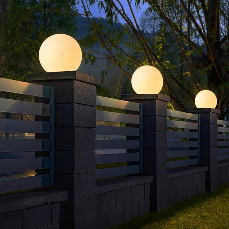 White globe pillar lights along a modern garden fence