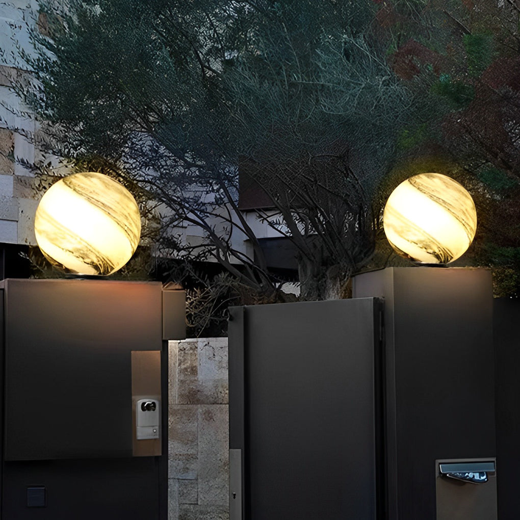 Globe pillar light glowing warm beside outdoor steps and plants