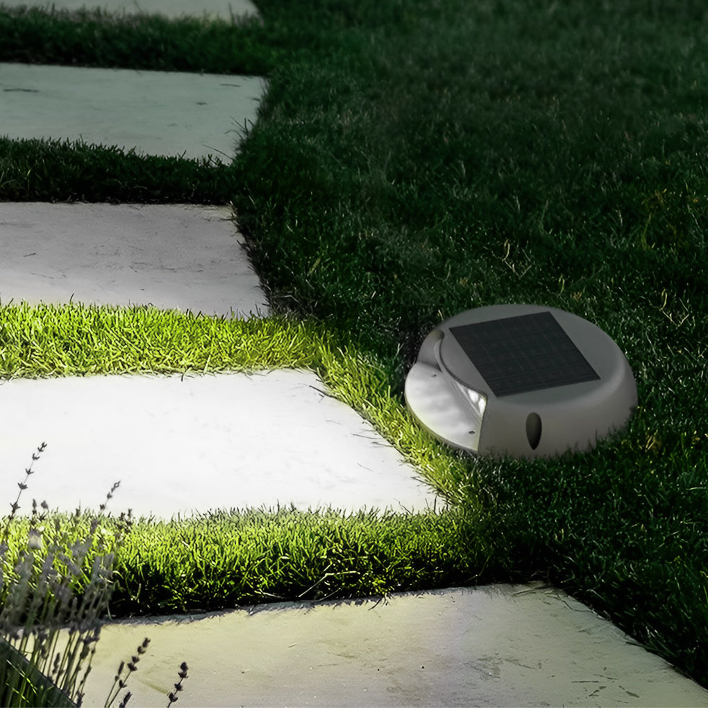Deck light glowing warm along a grass and stone path