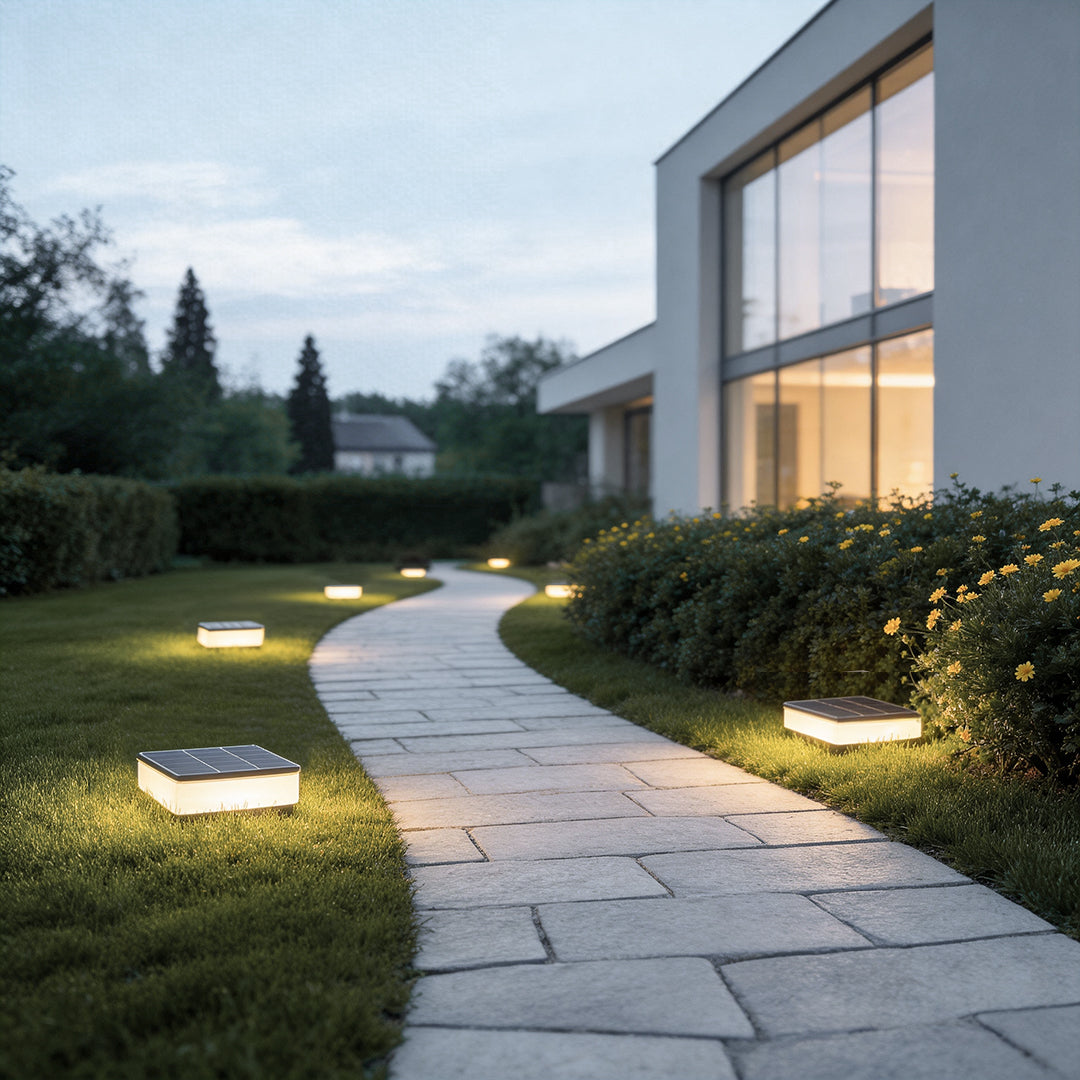 Solar ground disc lights giving a warm glow on a garden pathway