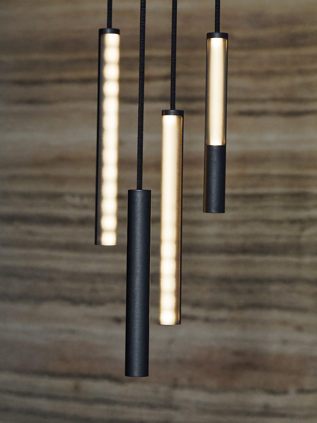 Detail of matte black cylindrical LED pendant tubes at staggered heights