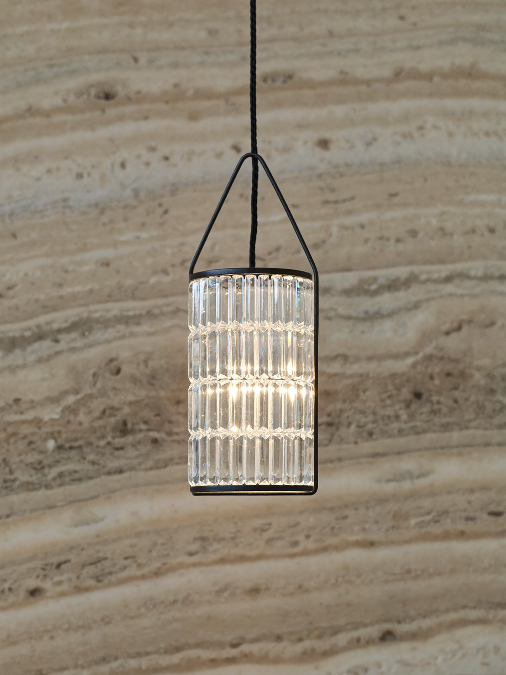 Close-up of a faceted crystal pendant light in a black iron frame