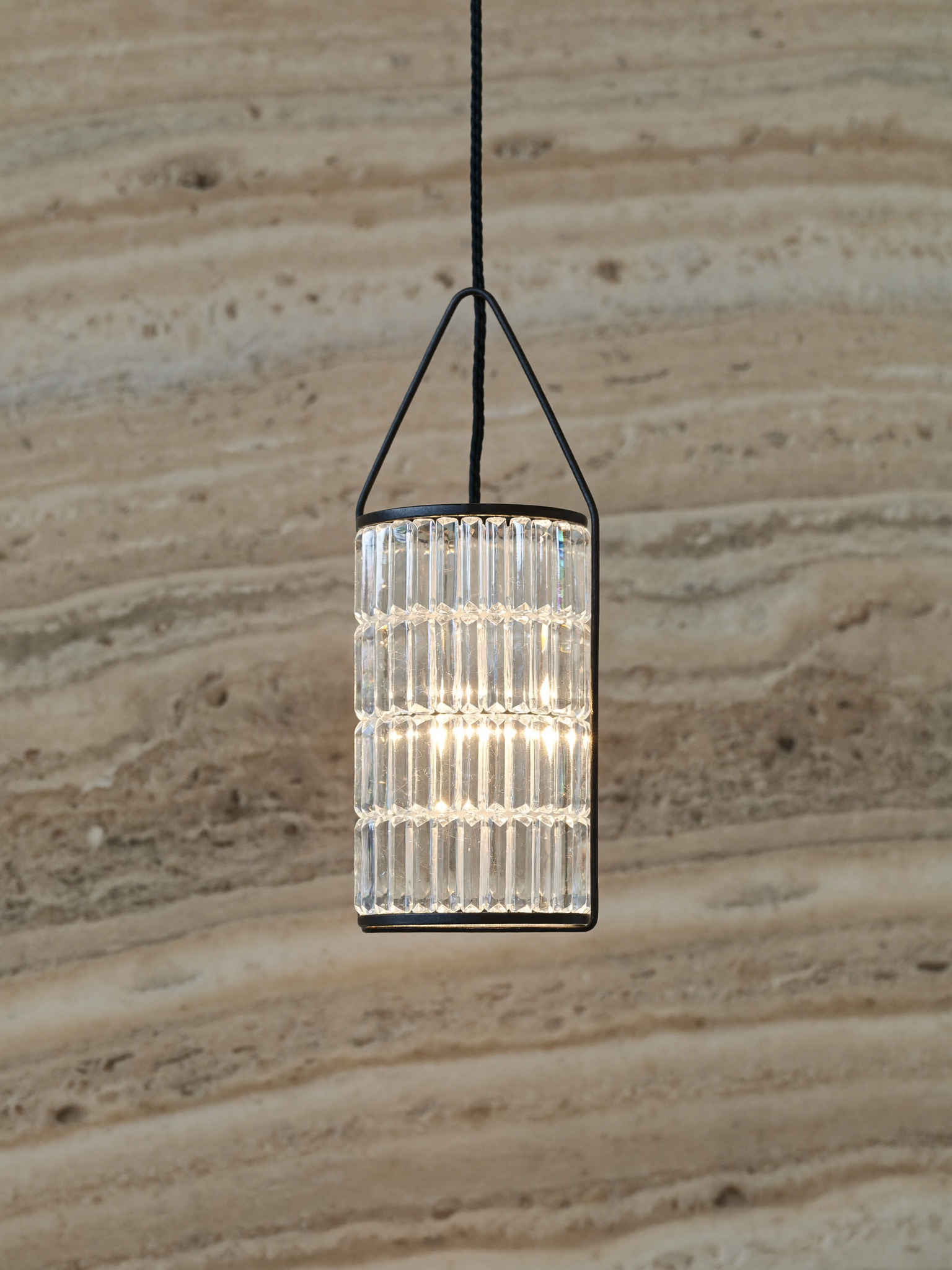 Close-up of a faceted crystal pendant light in a black iron frame