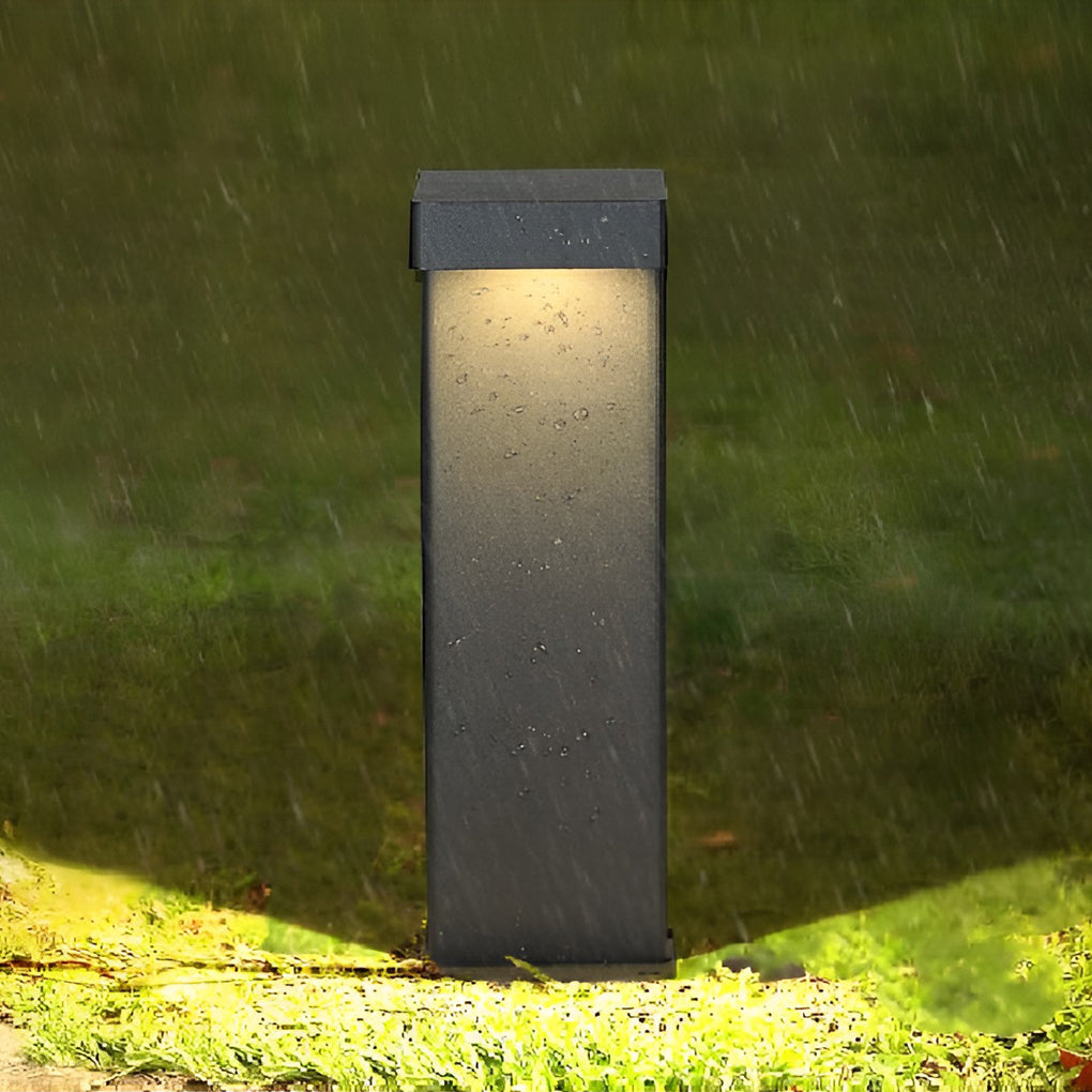 Modern black L-shaped light illuminating a garden pathway
