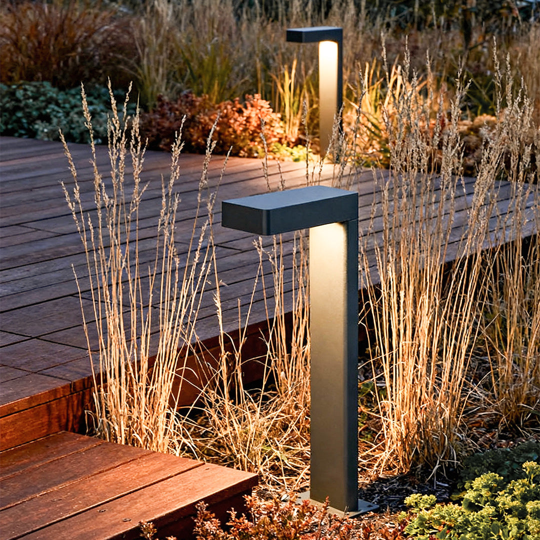 Sleek black L-shaped path light among plants on a garden pathway