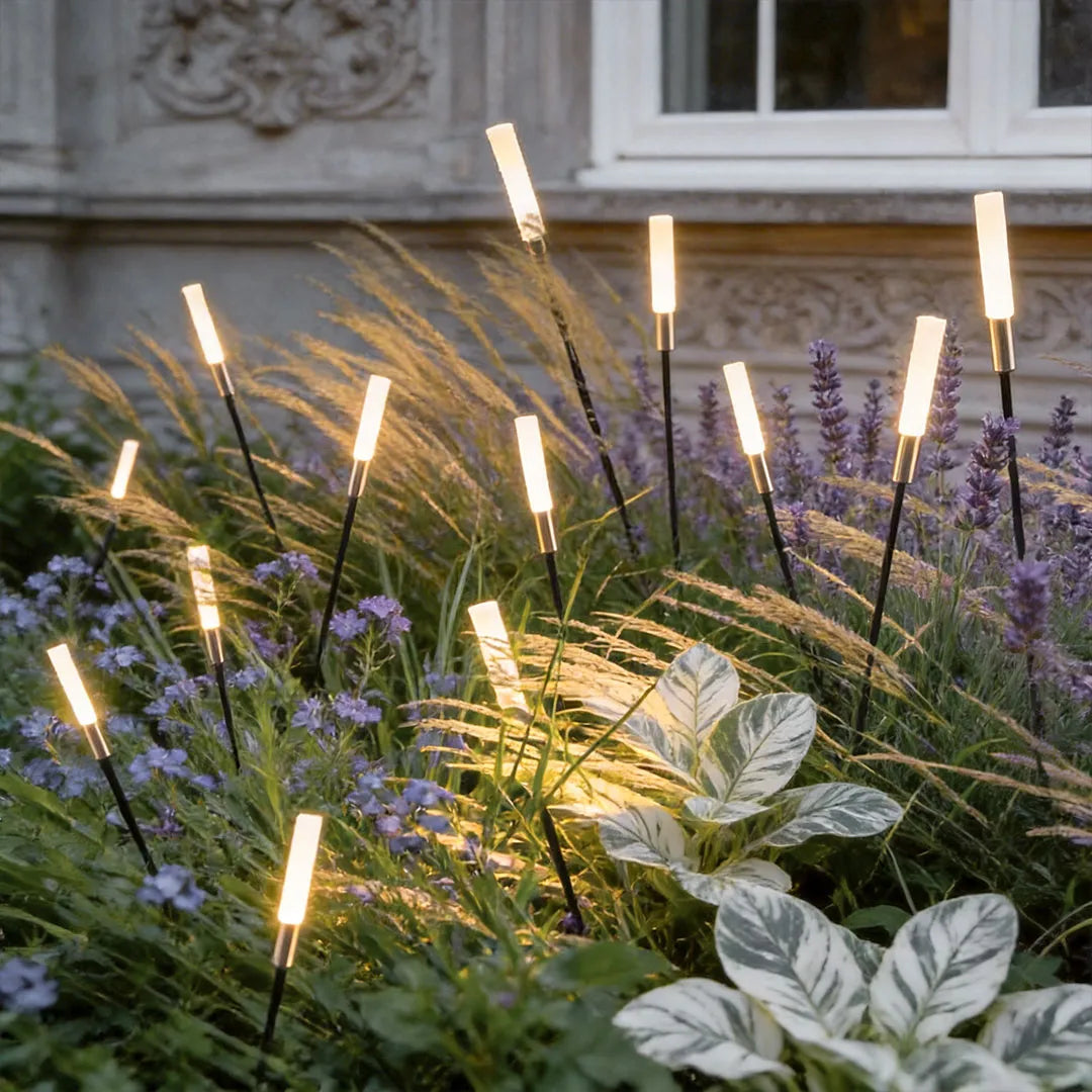 Spike lights standing among layered garden plants at night