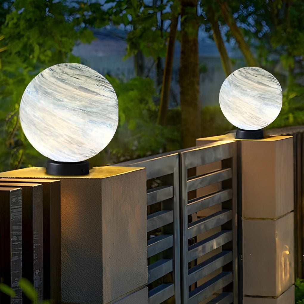 Marble globe pillar lights along a modern garden pathway at dusk