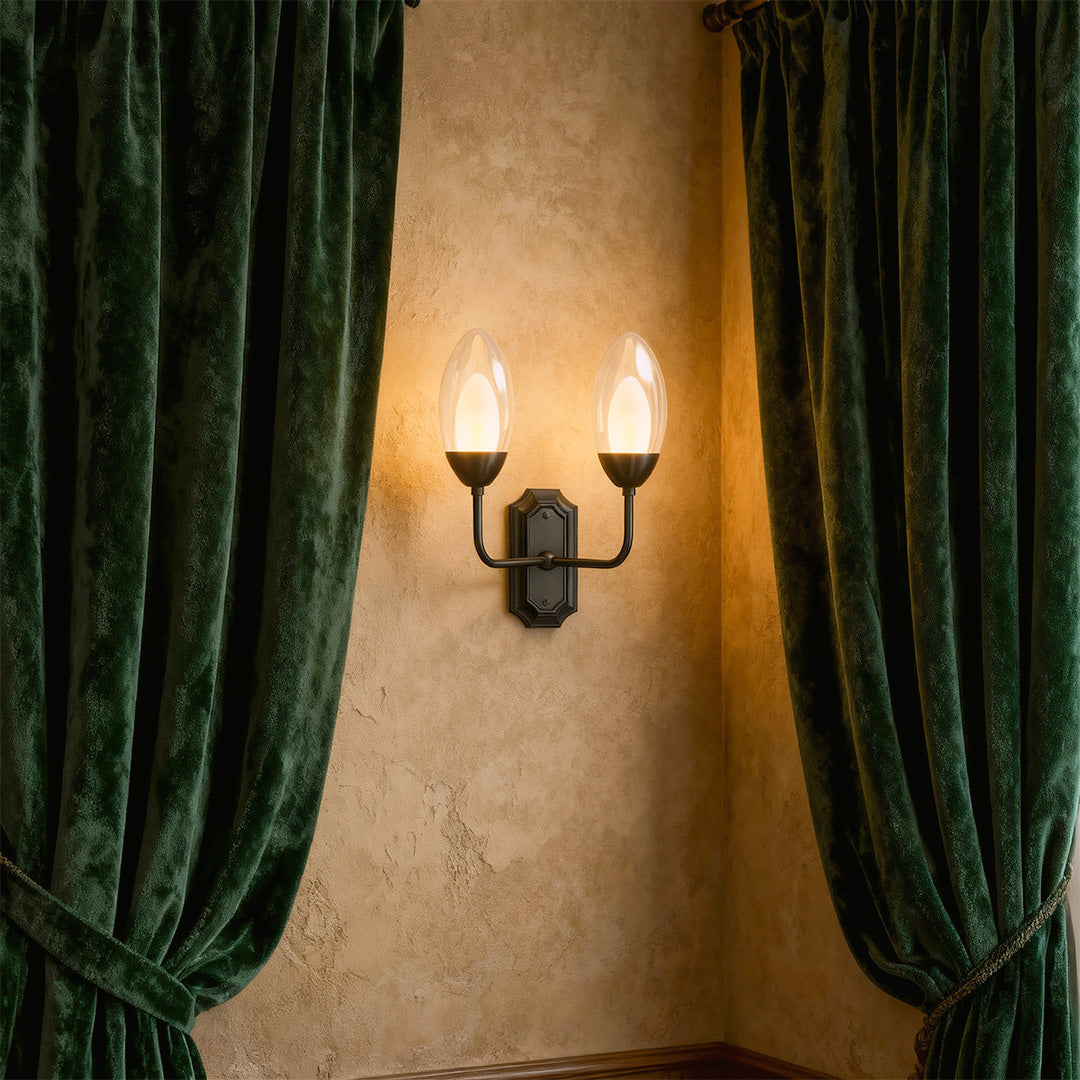 Glass wall light mounted beside green velvet curtains