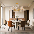 Globe chandelier hanging above warm rust dining chairs
