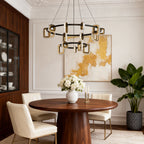 Gold tiered chandelier above a round wood table with colorful art