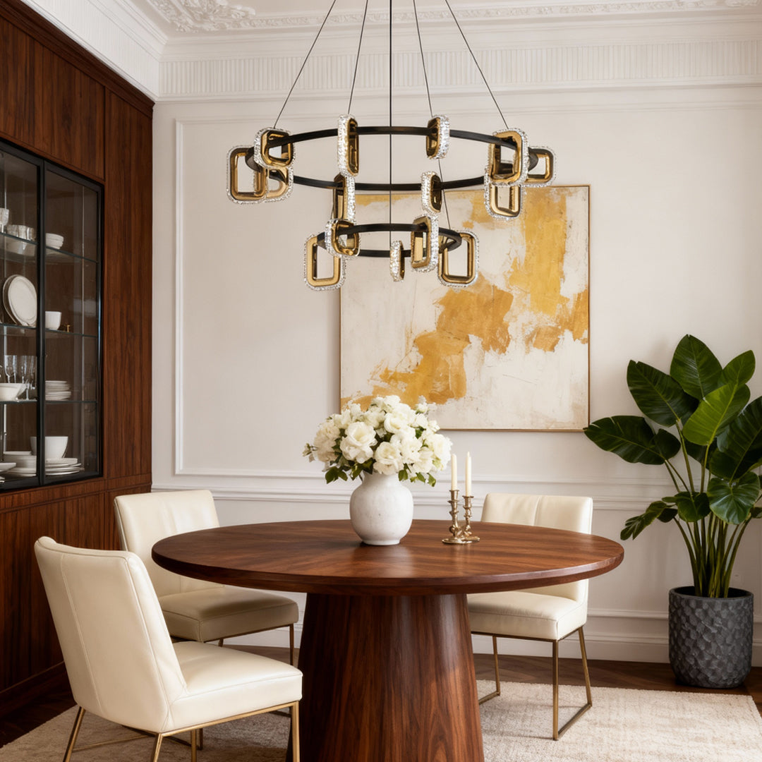 Gold tiered chandelier above a round wood table with colorful art