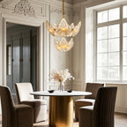 Large chandelier above a brass table with designer chairs
