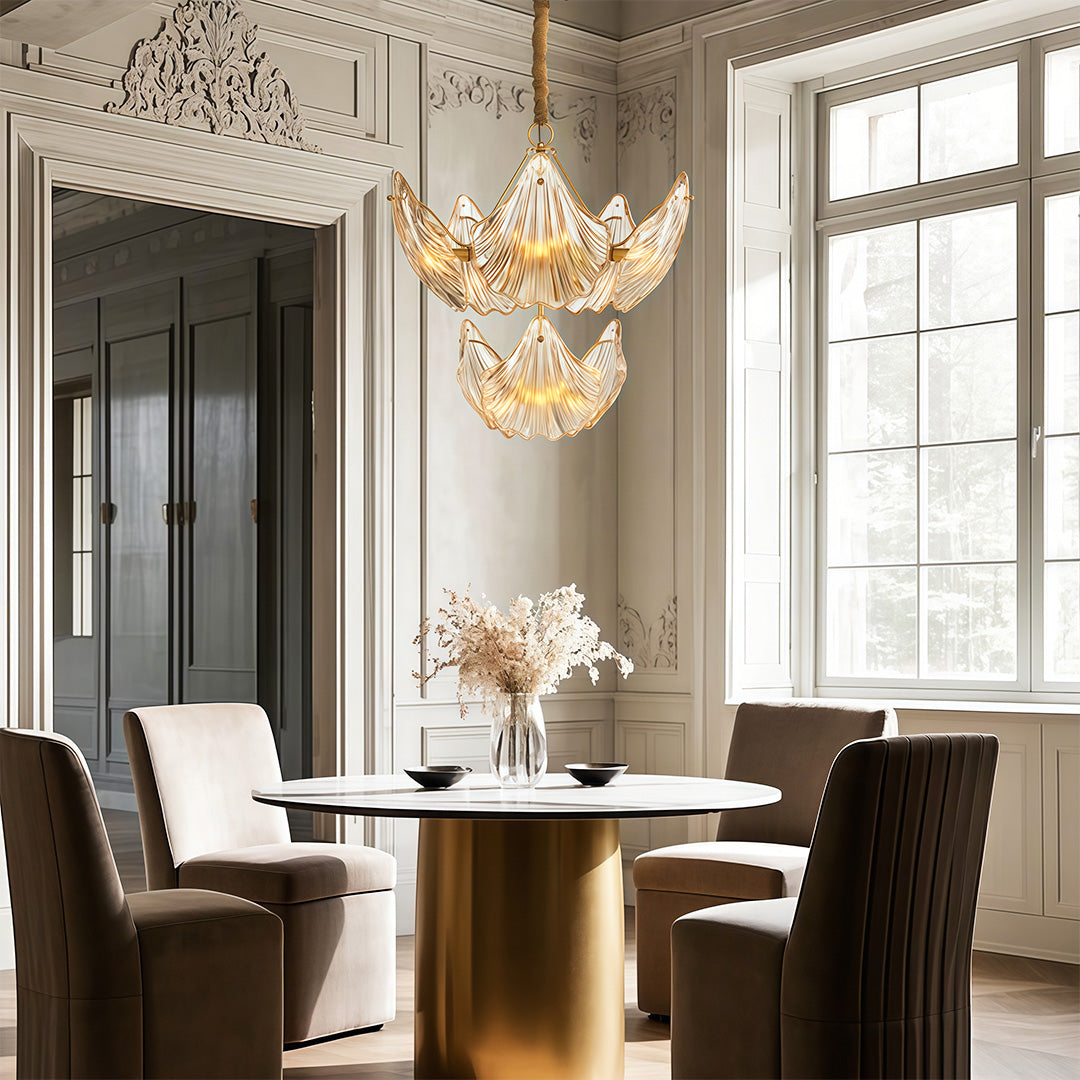 Large chandelier above a brass table with designer chairs