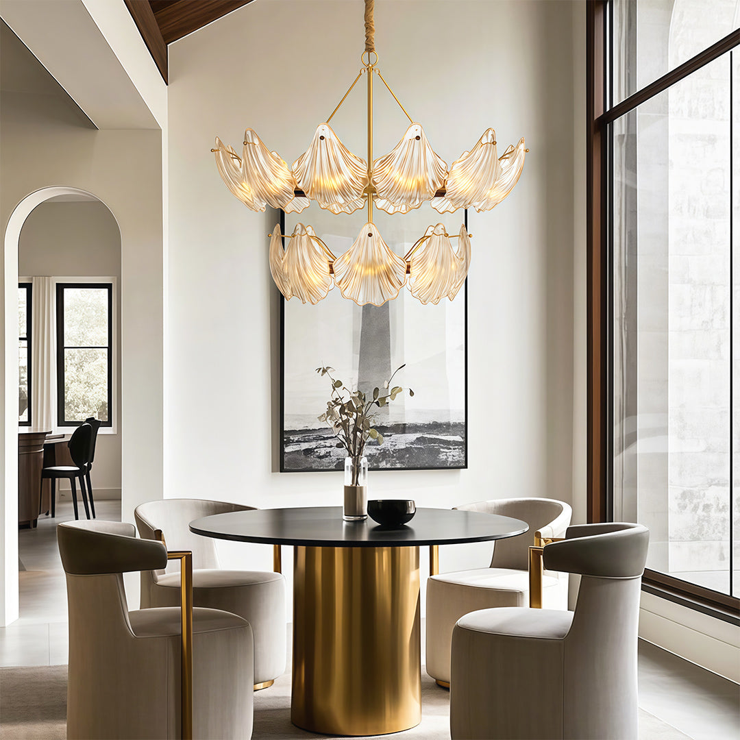 Large chandelier above a brass pedestal dining table