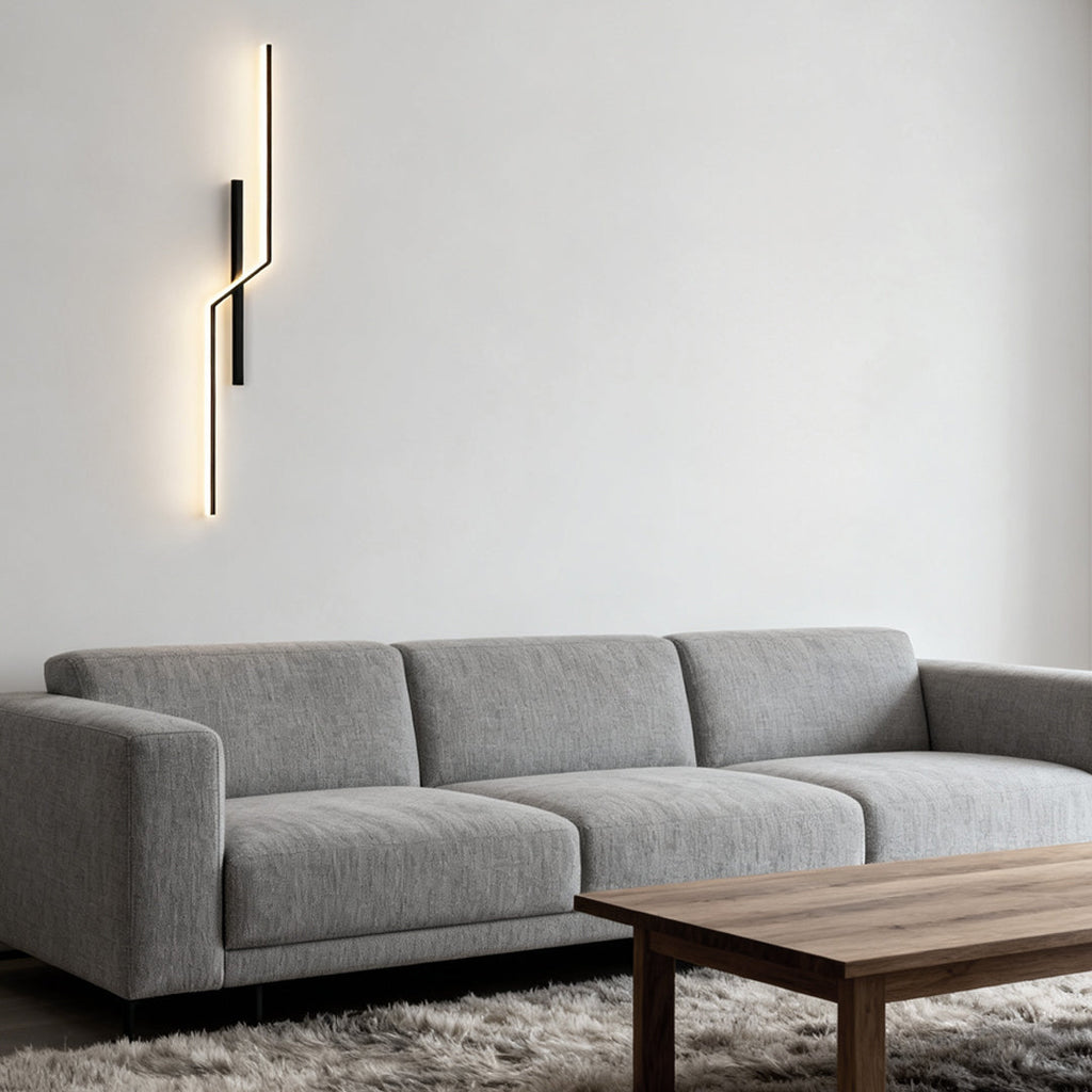 Linear wall sconce glowing above a living room sofa