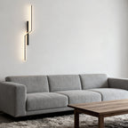 Linear wall sconce glowing above a living room sofa