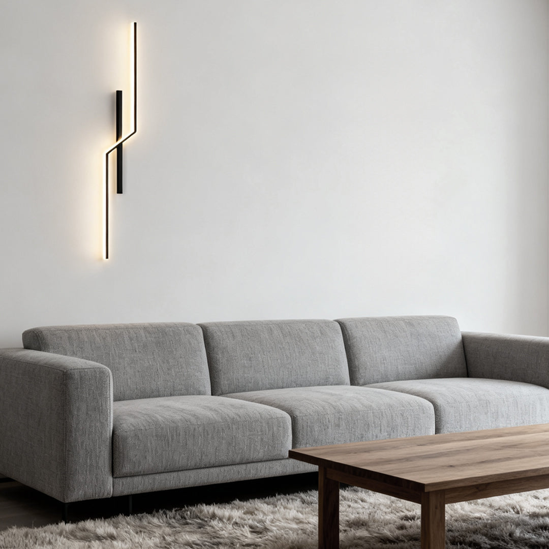 Linear wall sconce glowing above a living room sofa
