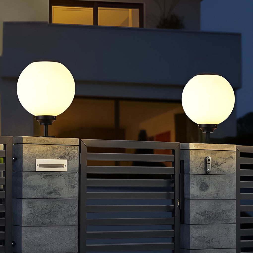 Spherical gate pillar light giving warm light at a residential entrance