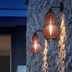Rattan pendant light hanging in front of a stone wall