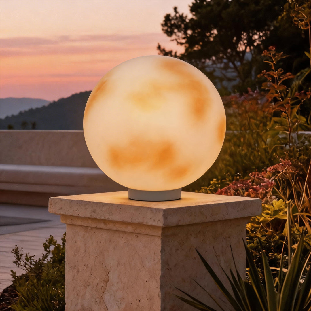 Moon globe pillar light glowing on a garden pedestal