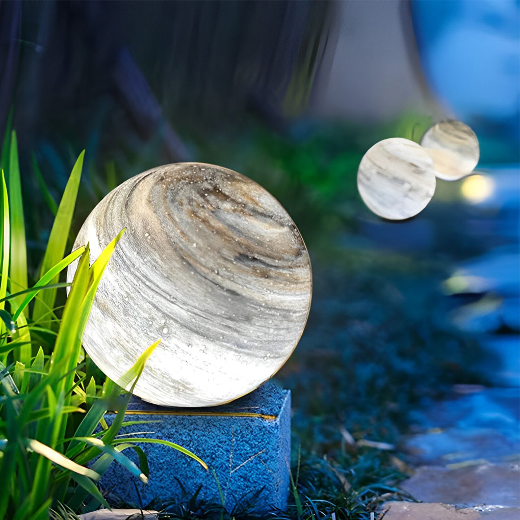 Natural marble globe pillar light in a garden setting