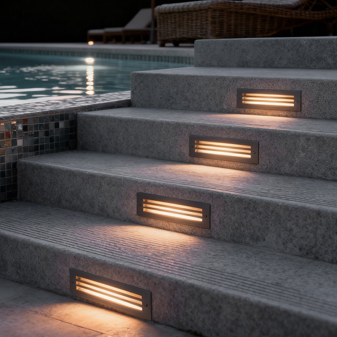 Recessed step light glowing in poolside concrete steps