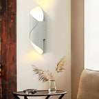 White and gold cylinder sconce against dark curtains