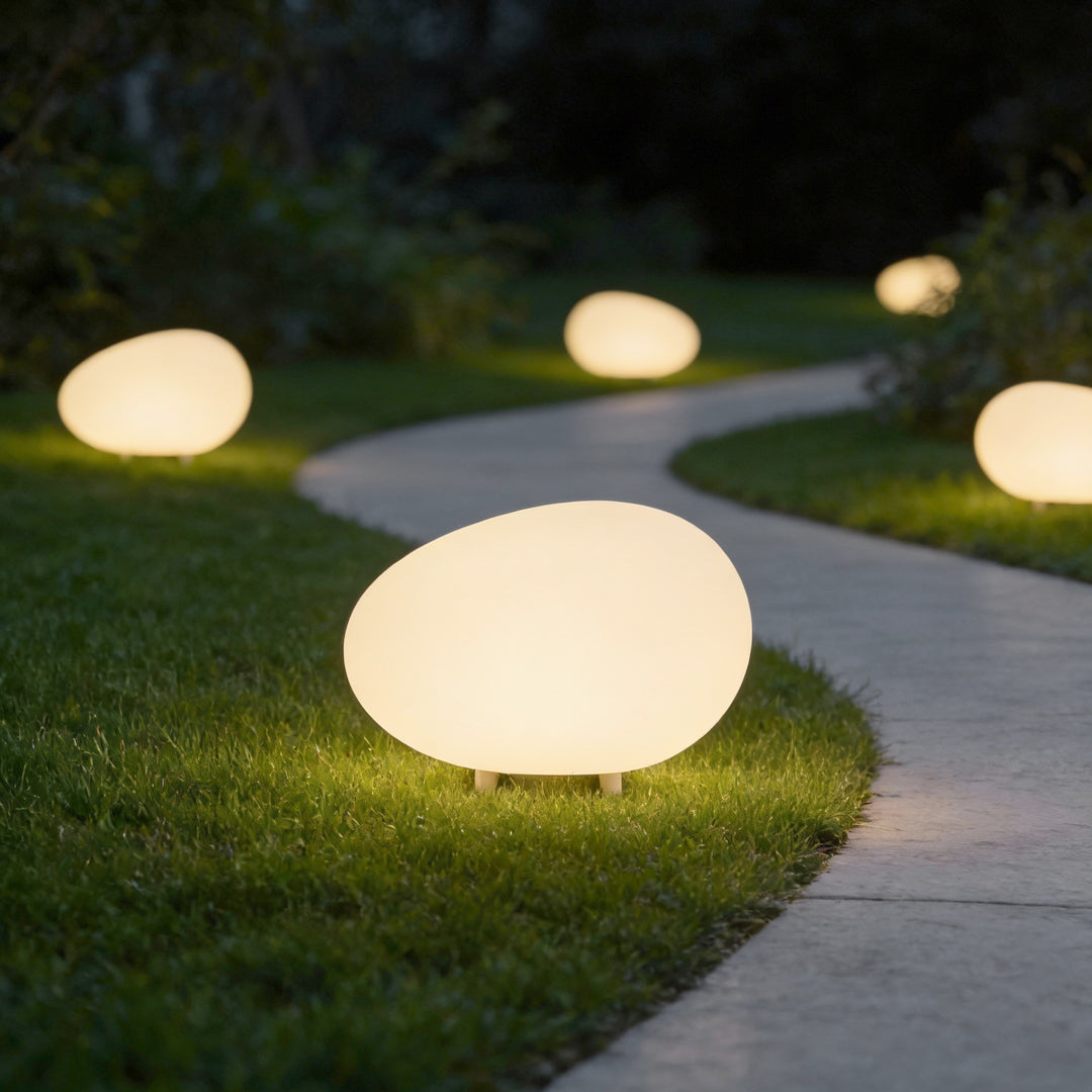 Pebble lights glowing softly along a garden pathway at dusk