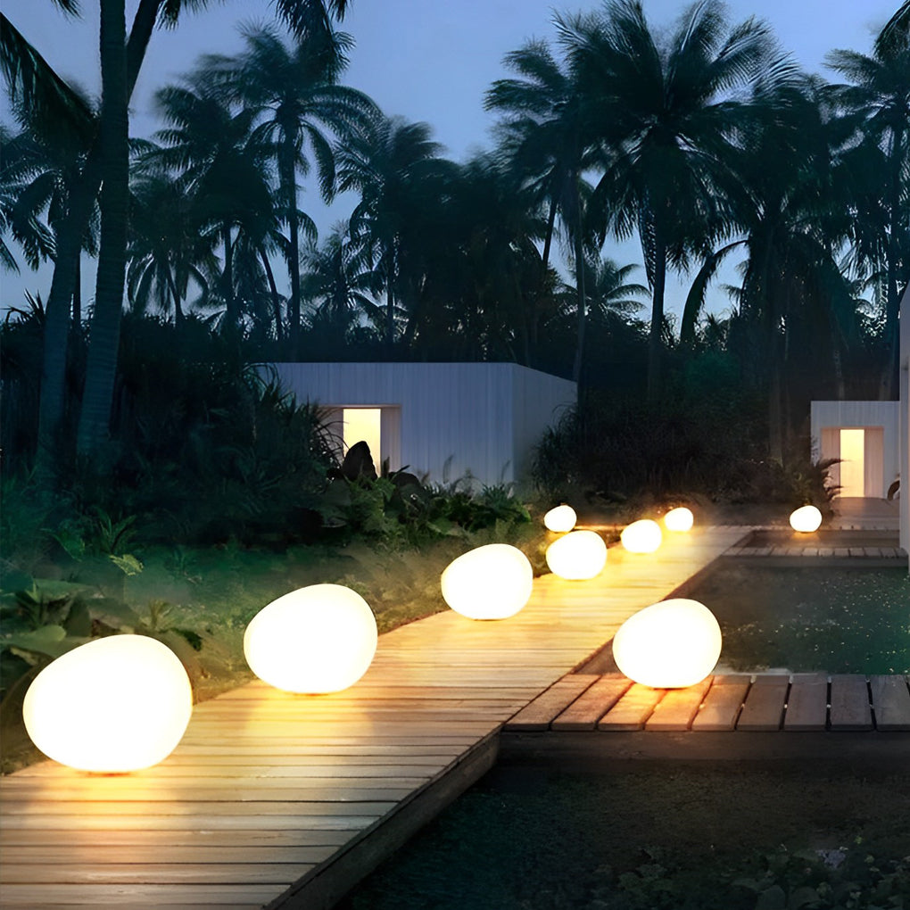 Pebble lights warmly illuminating a garden pathway edge