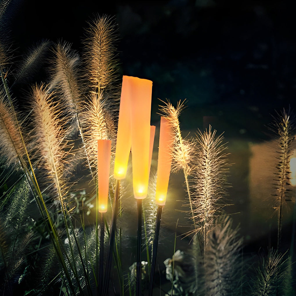 Reed lights glowing softly among decorative grasses in darkness