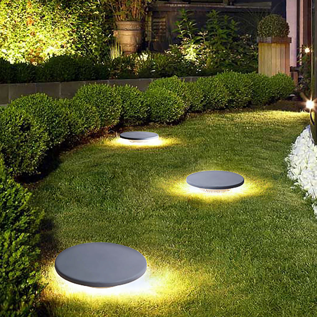 Round lawn lights illuminating the edge of a garden border
