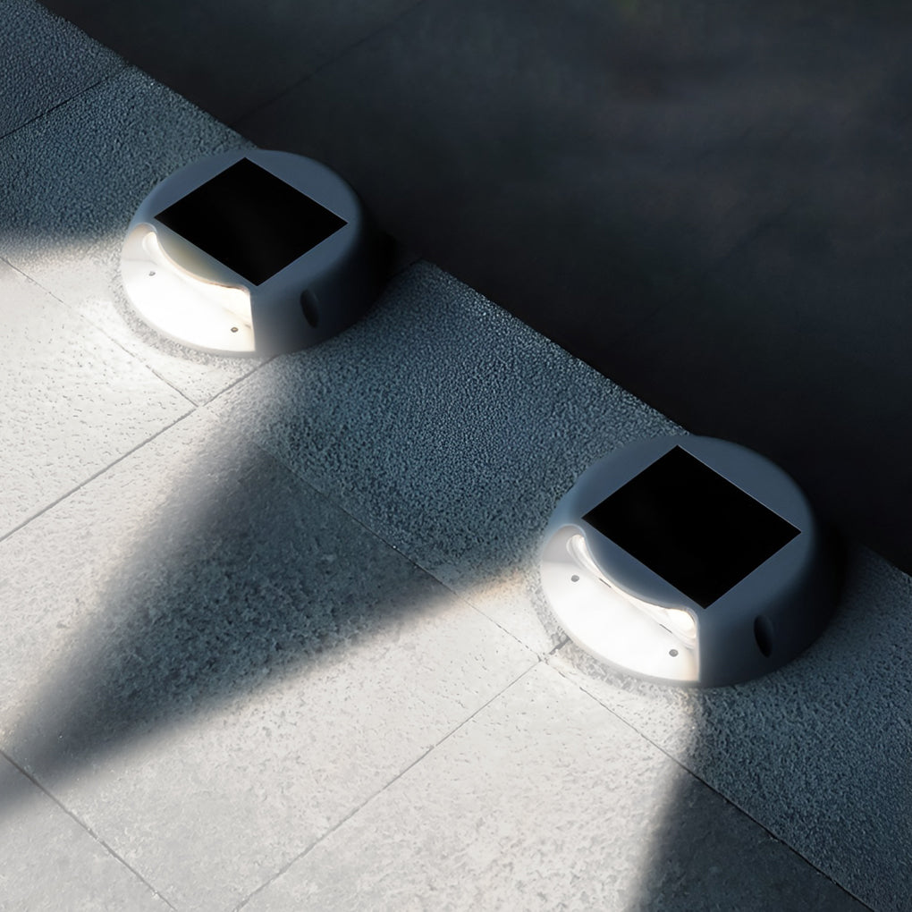 Round solar deck light recessed into a tiled edge