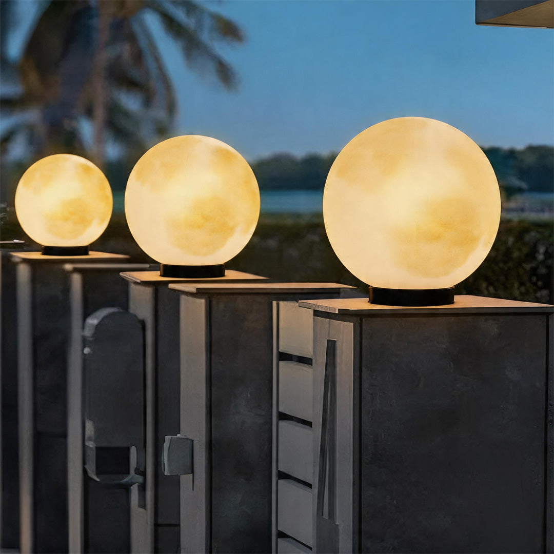 Row of glowing moon pillar lights along a dark grey fence