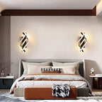 Spiral sconce giving warm light above a stylish bed