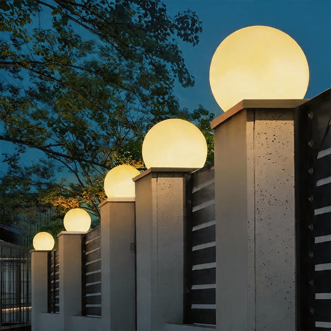 Moon pillar lights in various sizes along a garden fence