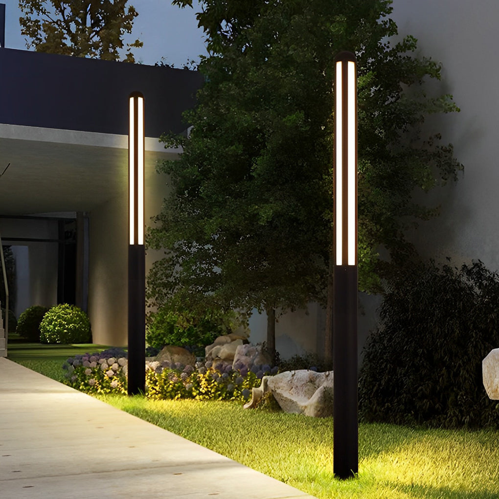 Tall bollard light at a driveway entrance among lush greenery