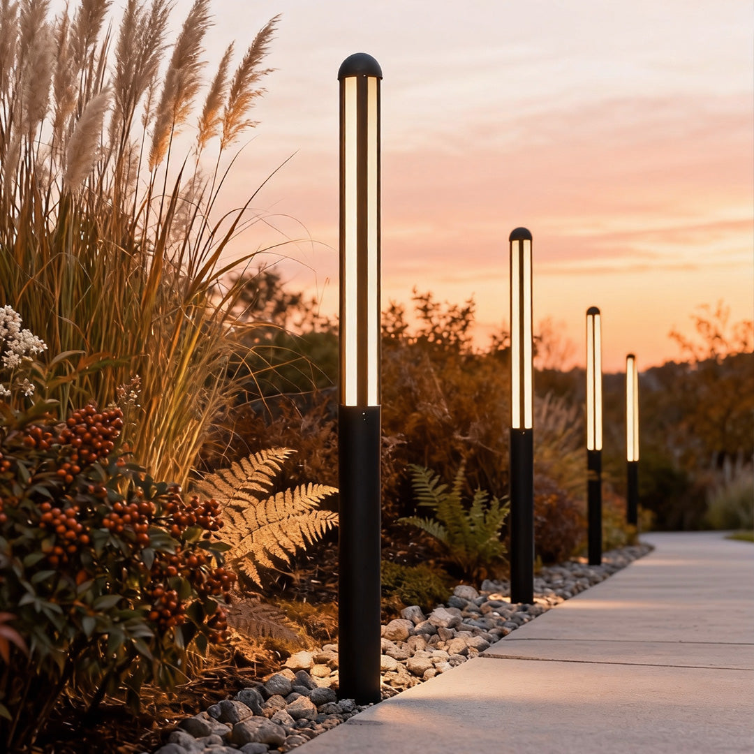 Tall bollard light on a pathway among ornamental grasses at sunset